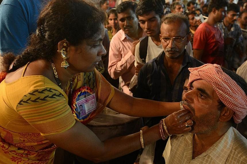 An Indian member of the Bathini Goud family (left) administers 'fish medicine' to a patient at the exhibition grounds in Hyderabad on June 8, 2014. -- PHOTO: AFP