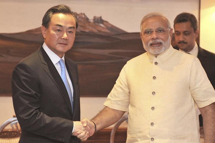 Chinese Foreign Minister Wang Yi (Left) shakes hands with Indian Prime Minister Narendra Modi during their meeting in New Delhi on June 9, 2014. Mr Wang promised on June 8, 2014 to help India's economic development and emphasised that the two countri