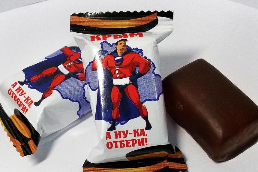 A handout photo provided on June 10, 2014, by Russian confectionery company Chocolate Traditions shows chocolate sweets with wrappers reading "Crimea. Just try to take it!" and displaying a Superman lookalike superhero in the colours of the Russian f