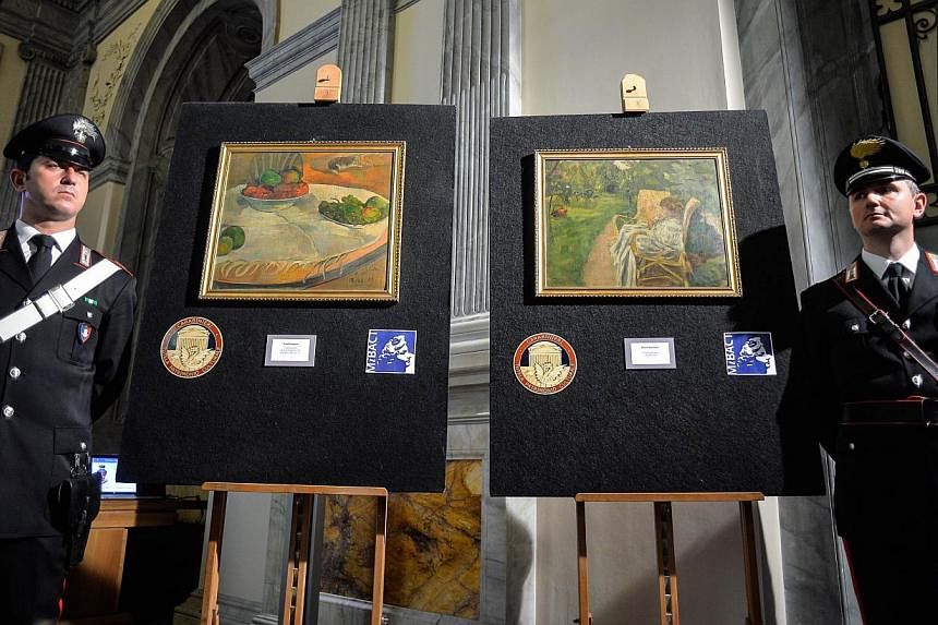 Carabinieri stand next to the two paintings stolen in London in the 1970s by French artists Paul Gauguin "Fruits sur une table ou nature au petit chien", (left) and Pierre Bonnard "La femme aux deux fauteuils" on April 2, 2014. -- PHOTO: AFP
