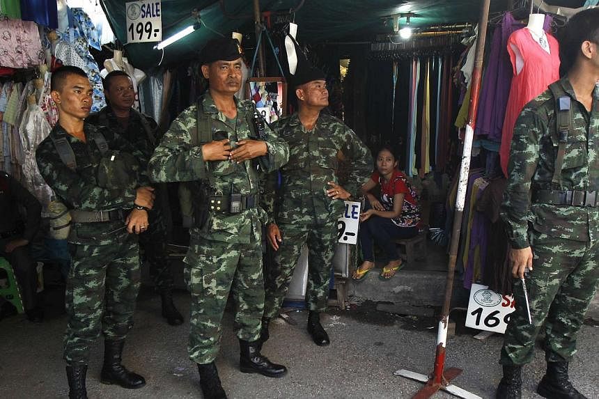 Soldiers stand guard at a shop at Chatuchak market in Bangkok on June 8, 2014.&nbsp;Thailand's military junta is giving away movie tickets this weekend to promote "love and harmony", a spokesman for the junta said on Wednesday, in its latest effort t