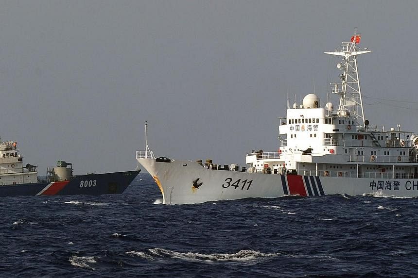 This picture taken from a Vietnam Coast Guard ship on May 14, 2014, shows a Vietnamese Coast Guard ship (left) being challenged by a China Coast Guard ship near to the site of a Chinese drilling oil rig (right, background) being installed in the disp
