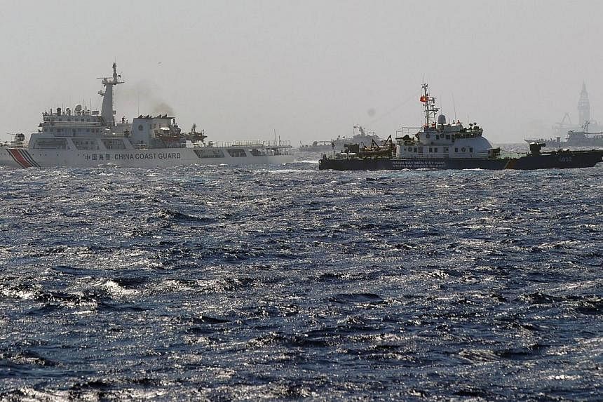 This picture taken from a Vietnam Coast Guard ship on May 14, 2014, shows a Vietnam Coast Guard ship (second right, dark blue) trying to make way amongst several China Coast Guard ships near to the site of a Chinese drilling oil rig (right, backgroun