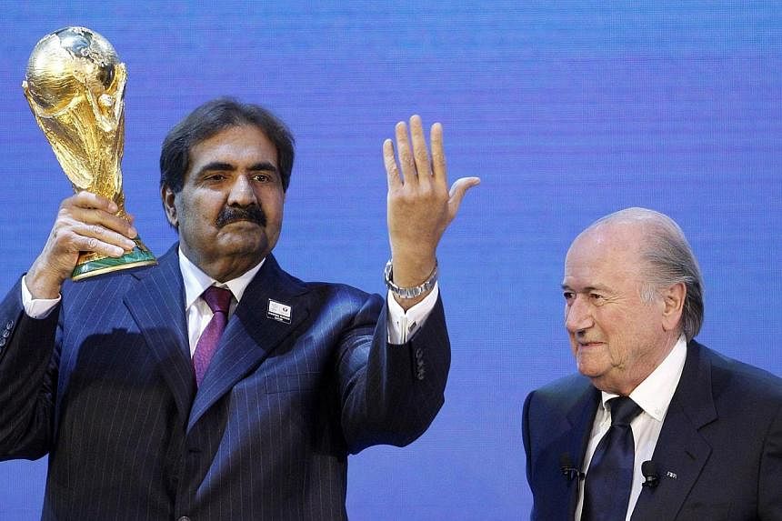 Qatar's Emir Sheikh Hamad bin Khalifa al Thani (left) holds up a copy of the World Cup he received from Fifa President Joseph S. Blatter (right) after the announcement that Qatar is going to be host nation for the Fifa World Cup 2022, in Zurich on De