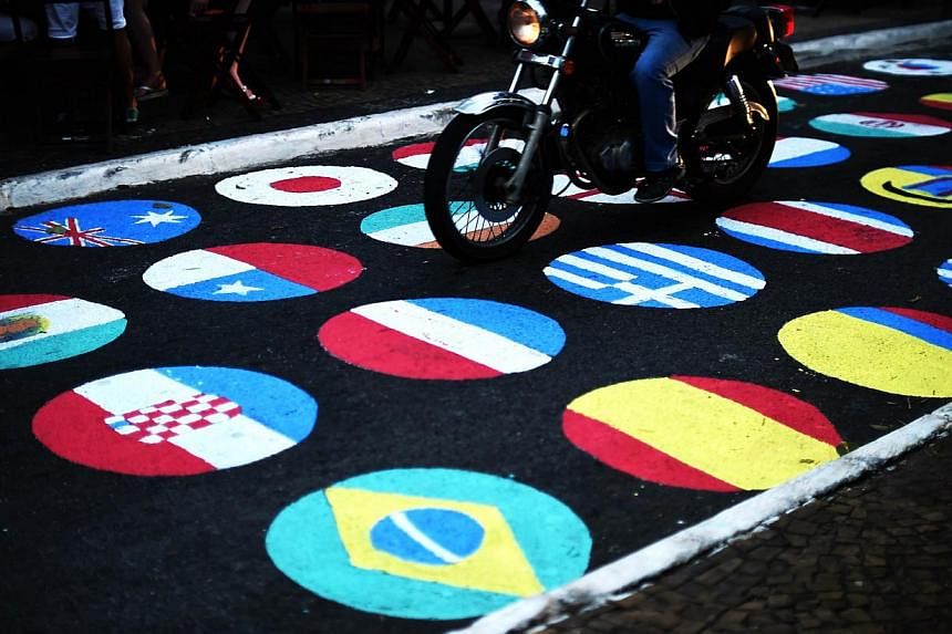 A man rides his motorcycle through a street painted with the national flags of the football teams qualified for the 2014 Fifa World Cup in Itu on June 11, 2014. -- PHOTO: AFP