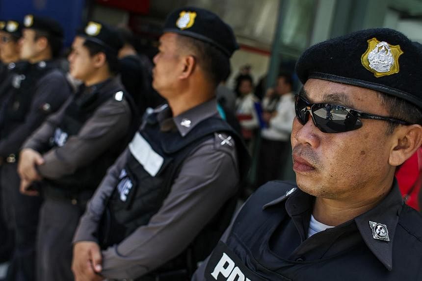 Police officers stand guard at a shopping mall in Bangkok on June 8, 2014. -- PHOTO: REUTERS
