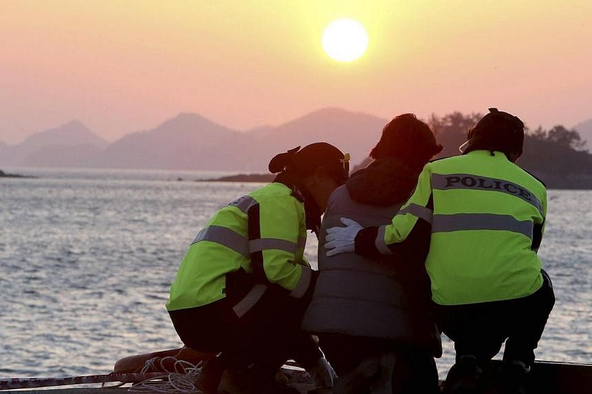 Policewomen comfort a family member (centre) of missing passengers onboard the capsized passenger ship Sewol, as she waits for news from a search and rescue operation team, during sunset at a port in Jindo on April 30, 2014. -- PHOTO: REUTERS