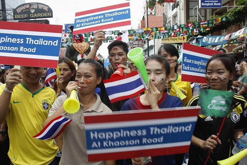 Workers hold placards during a celebration to boost tourism, along the Khaosan tourist street in Bangkok on June 13, 2014.&nbsp;Thailand's military government lifted a curfew nationwide on Friday, June 13, 2014, citing the absence of any violence and