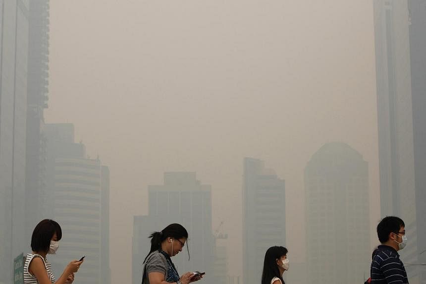 Office workers wearing masks make their way to work in Singapore's central business district on June 21, 2013. -- PHOTO: REUTERS