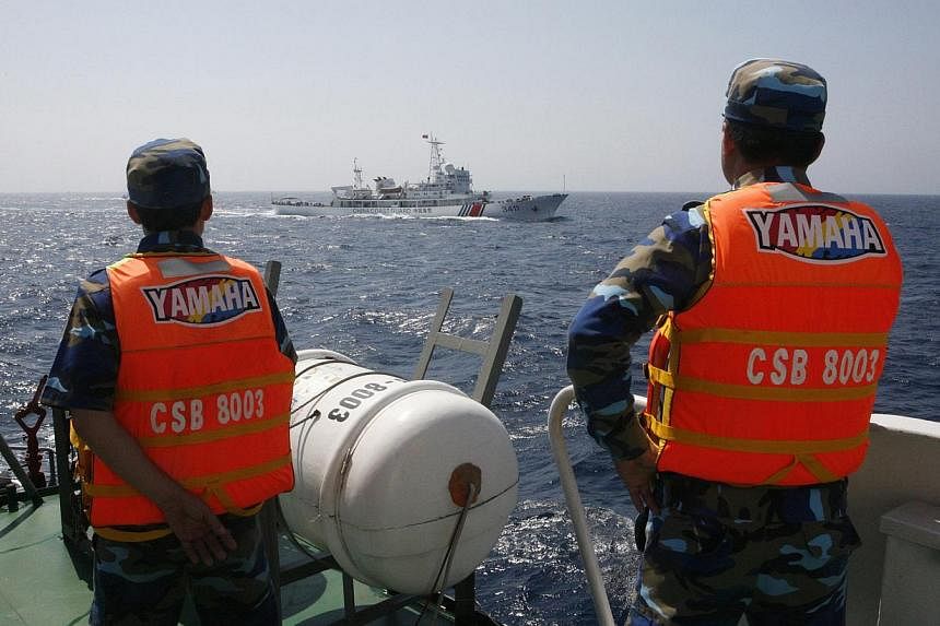 Officers of the Vietnamese Marine Guard monitoring a Chinese coast guard vessel (top) on the South China Sea, about 210km offshore of Vietnam in this May 15, 2014 file photo. A Chinese official said on Friday that China will never send military force