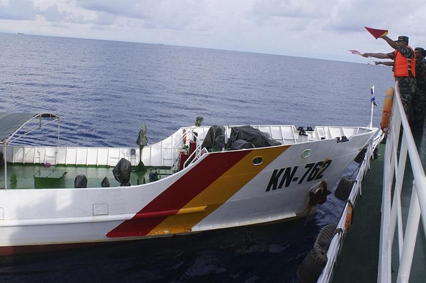 A Chinese maritime policeman (right) using flags to signal to Vietnamese ship KN-762 (left), which according to the Chinese authorities collided with Chinese coast guard ship 46001 in South China Sea, in this handout dated May 2, 2014 provided by the