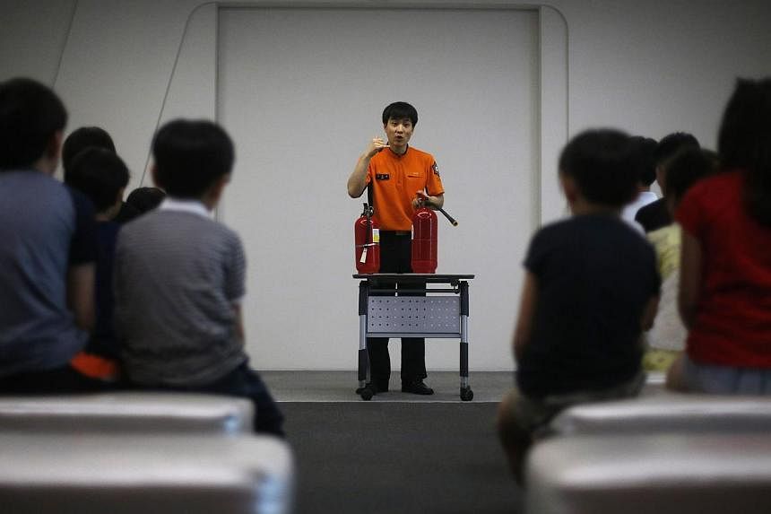 A fire officer demonstrates how to use a fire extinguisher to children during a fire safety course at a safety experience centre in Seoul on June 4, 2014. -- PHOTO: REUTERS
