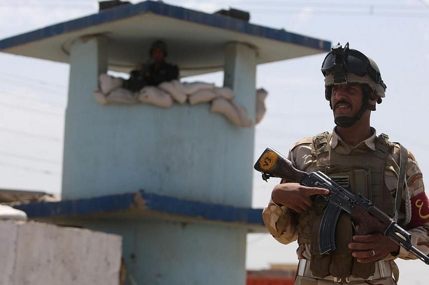 An Iraqi soldier stands guard at a checkpoint in the Iraqi town of Taji, at the entrance of Baghdad, on June 13, 2014, as security forces are bolstering defenses in the capital. -- PHOTO: AFP