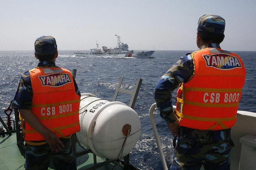 Vietnamese marine guard officers monitoring a Chinese coast guard vessel in the South China Sea, about 210km offshore of Vietnam, in this May 15 photo. China's placement of an oil rig in contested waters has raised tensions.
