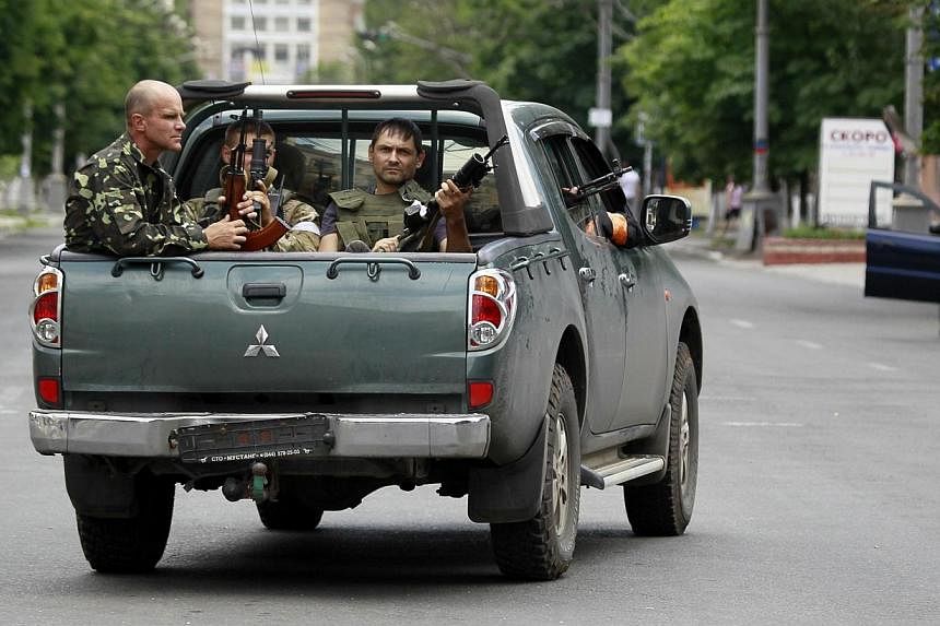 Ukrainian troops ride in the back of a pick-up truck in the eastern port city of Mariupol on June 13, 2014. Forty-nine Ukrainian military personnel were killed when rebels shot down a cargo plane during the night over the airport of the eastern city 