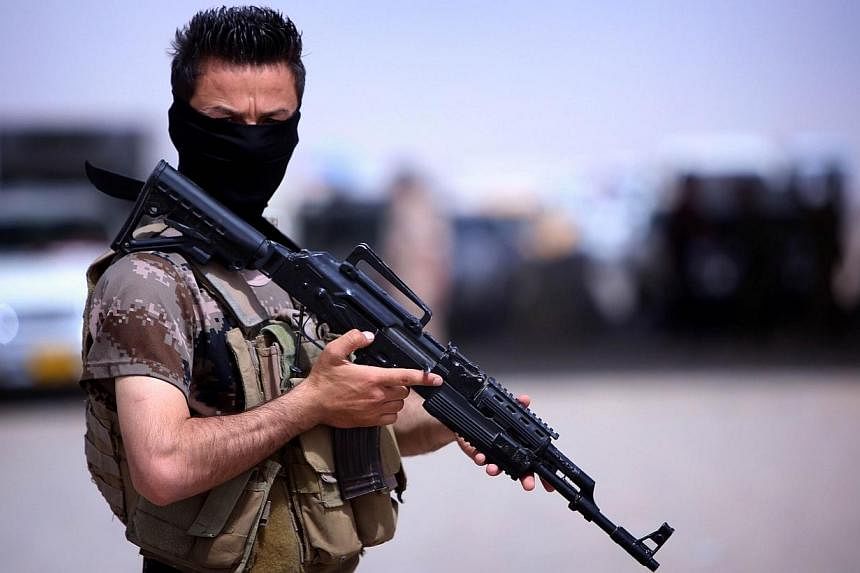 A masked Pershmerga fighter from Iraq's autonomous Kurdish region guards a temporary camp set up to shelter Iraqis fleeing violence in the northern Nineveh province, in Aski kalak, 40km west of the region's capital Arbil, on June 13, 2014. -- PHOTO: 