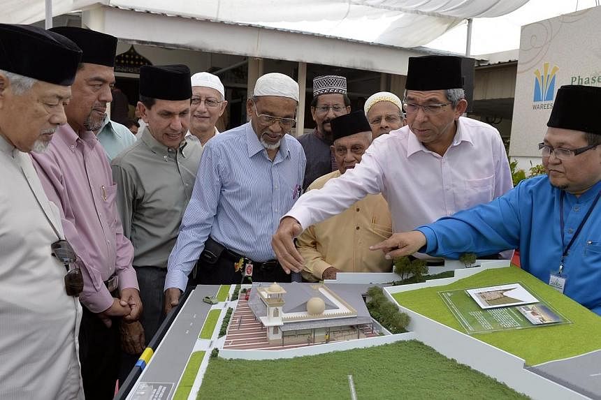Minister for Communications and Information and Minister-in-charge of Muslim Affairs, Dr Yaacob Ibrahim (second from right) and guests looking at a model of the new proposed upgrade of the Al Huda Mosque .&nbsp;Universal health insurance plan Medishi