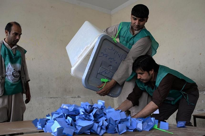 Afghan election workers empty a ballot box during the counting process at a polling station in Mazar-i-Sharif on June 14, 2014.&nbsp;A roadside bomb killed 11 people including five election workers in northern Afghanistan, officials said Sunday, June