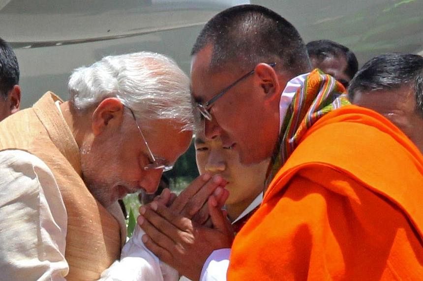 Indian Prime Minister Narendra Modi (left) gestures as he is met by Bhutanese Prime Minister Tshering Tobgay (right) at Paro Airport on June 15, 2014.&nbsp;&nbsp;India's Prime Minister Narendra Modi received a grand welcome to Bhutan on Sunday, June 