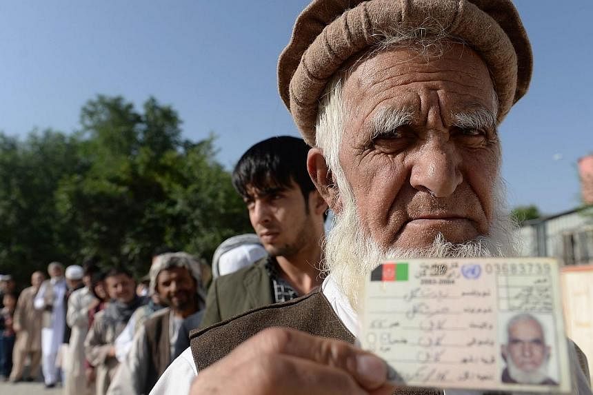 An Afghan resident wanting to vote poses for a photograph with his identity card as he waits for voting to start at a polling centre in Kabul on June 14, 2014.&nbsp;The White House welcomed Afghanistan’s presidential run-off election on Saturday as