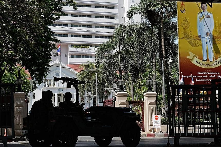 Thai army soldiers secure an area in front of the Royal Thai Police headquarters, adorned with a portrait of King Bhumibol Adulyadej (right). Thailand’s military is bolstering its self-designated role as protector of the monarchy by stepping up “