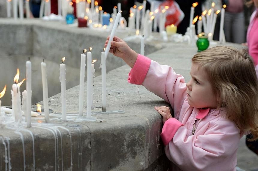 A girl places a candle during a memorial ceremony for the people killed when a Ukrainian military plane was shot by pro-Russian armed separatist militants on June 14, 2014, in the western Ukrainian city of Lviv. -- PHOTO: AFP&nbsp;