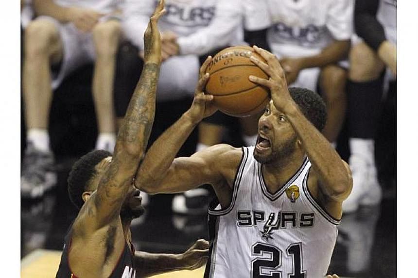 Tim Duncan (right) of the San Antonio Spurs shoots against Udonis Haslem of the Miami Heat during Game 5 of the NBA Finals on June15, 2014 in San Antonio,Texas. -- PHOTO: AFP