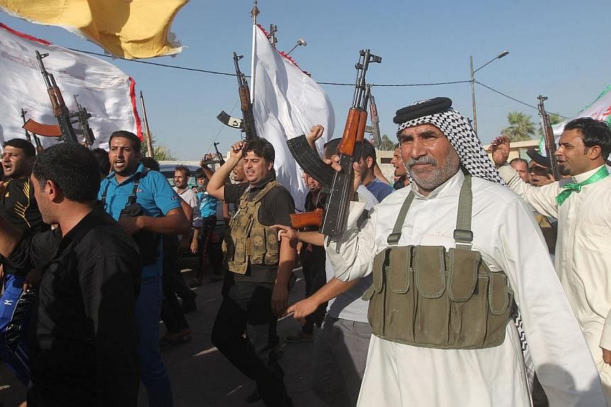 Iraqi tribes men carry their weapons as they gather, volunteering to fight along side the Iraqi security forces against Jihadist militants who have taken over several northern Iraqi cities, in the capital Baghdad, on June 15 2014. -- PHOTO: AFP