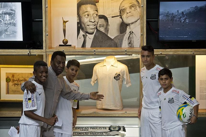 Brazilian football legend Edson Arantes do Nascimento (second from left), known as Pele, poses with young players during the inauguration of the Pele Museum, in Santos, some 70 km from Sao Paulo, Brazil, on June 15, 2014. -- PHOTO: AFP