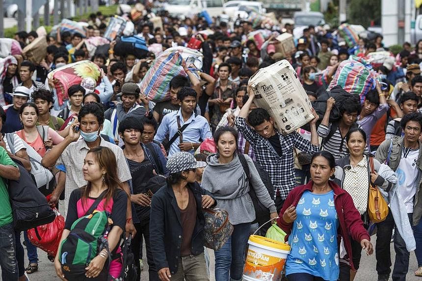 Cambodian migrant workers carry their belongings as they walk to cross the border at Aranyaprathet in Sa Kaew June 15, 2014. The International Organization for Migration (IOM) estimates that over the past week 100,000 Cambodians have poured over the 