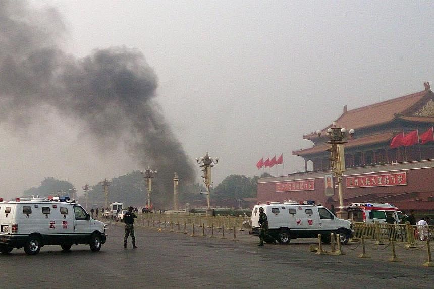 This file photo taken on Oct 28, 2013 shows police cars blocking off the roads leading into Tiananmen Square as smoke rises into the air after a vehicle loaded with petrol crashed in front of Tiananmen Gate in Beijing in an attack which left two peop