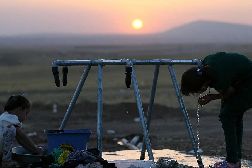 Iraqi children wash clothes and drink water at a temporary camp set up to house civilians fleeing violence, in Iraq's northern Nineveh province. Shiite Iran will consider working with longtime foe the United States if it takes the lead in helping pus