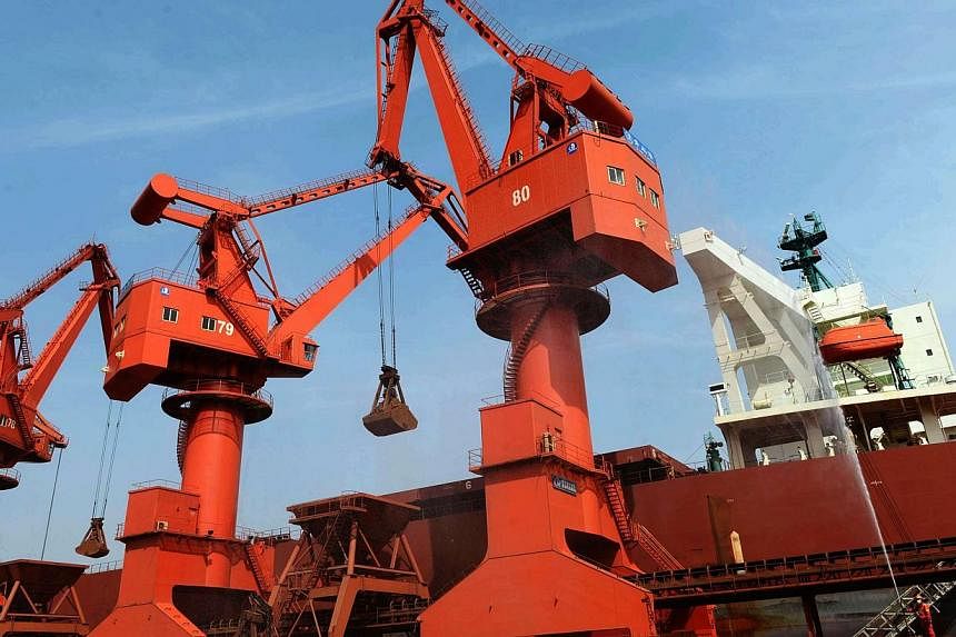 Iron ore being unloaded on a port in Qingdao, east China's Shandong province, in May 2014. -- PHOTO: AFP