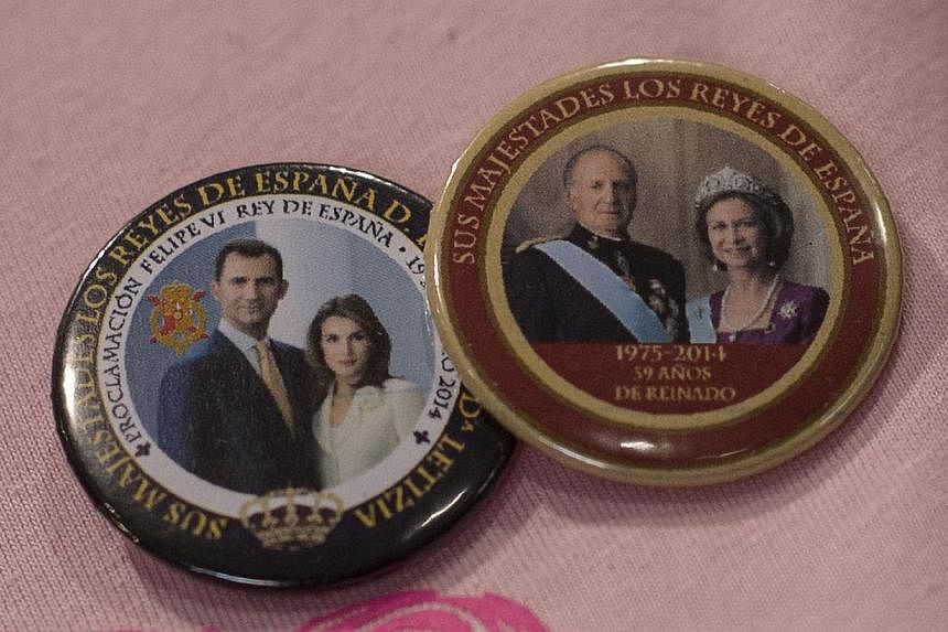 A picture taken on June 14, 2014 shows a badges with portraits of Spain's king-in-waiting, Prince Felipe, and his wife Letizia and Spain's King Juan Carlos and Queen Sofia at a souvenir shop in Madrid. -- PHOTO: AFP