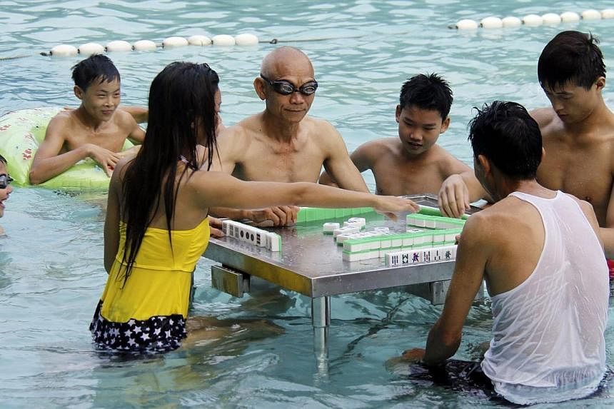 Residents play mahjong in a swimming pool to provide relief from the hot weather in Foshan, Guangdong province on Monday, June 16, 2014. The temperature in Foshan reached 35 deg C on Monday. -- PHOTO: REUTERS