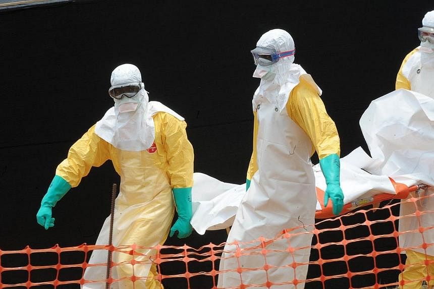 A file photo taken on April 1, 2014 shows staff of the "Doctors without Borders" ('Medecin sans frontieres) medical aid organisation carrying the body of a person killed by viral haemorrhagic fever, at a center for victims of the Ebola virus in Gueke
