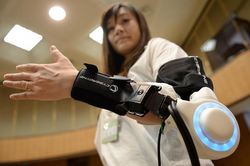 An official of Kawasaki City demonstrates a new powered exoskeleton to assist movement of an arm developed by Japan's robot suit venture Cyberdyne during a press conference in Kawasaki, suburb of Tokyo, on June 18, 2014.&nbsp;A Japanese robot-maker o