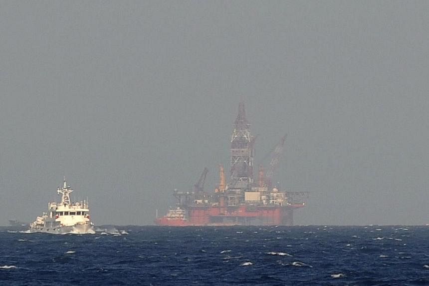A Vietnamese coast guard ship shows a Chinese coast guard vessel (left) sailing near China's oil drilling rig in disputed waters in the South China Sea on May 14, 2014. -- PHOTO: AFP