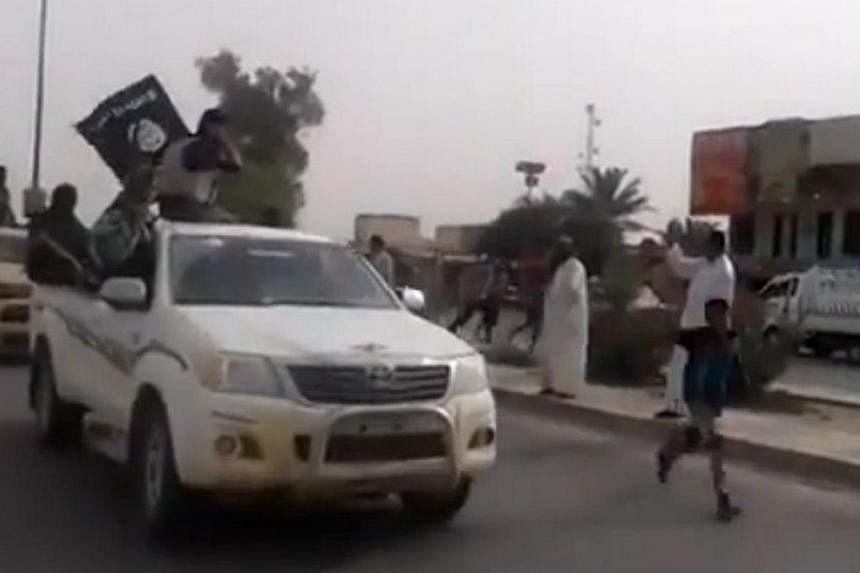 An image grab taken from a video uploaded on Youtube on June 17, 2014, allegedly shows militants from the Islamic State of Iraq and the Levant (ISIL) parading with their group's flag in the northern city of Baiji in the in Salaheddin province.&nbsp;P
