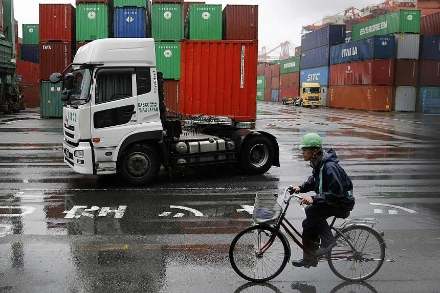 A worker rides a bicycle in a container area at a port in Tokyo May 21, 2014. Japan's exports suffered their first annual decline that month. -- PHOTO: REUTERS&nbsp;