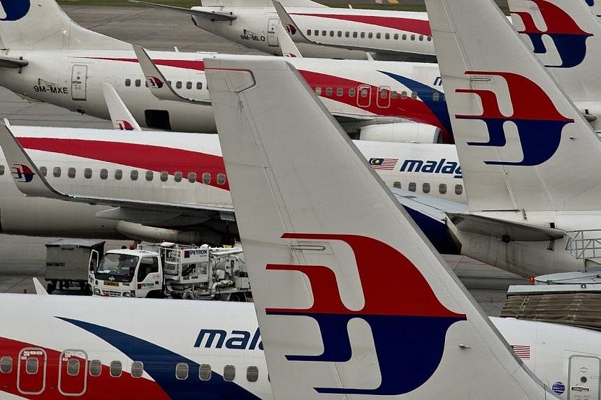 Airport groundstaff walk past Malaysia Airlines planes parked on the tarmac at the Kuala Lumpur International Airport in Sepang on June 17, 2014.&nbsp;Malaysia Airlines (MAS) has been told by Malaysia's Transport Ministry to give Muslim stewardesses 