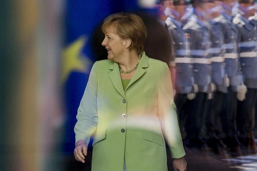 Honour guards are reflected on a window as German Chancellor Angela Merkel arrives to meet Tunisia's Prime Minister Mehdi Jomaa (not pictured) at the Chancellery in Berlin on June 18, 2014.&nbsp;German Chancellor Angela Merkel said on Wednesday, June