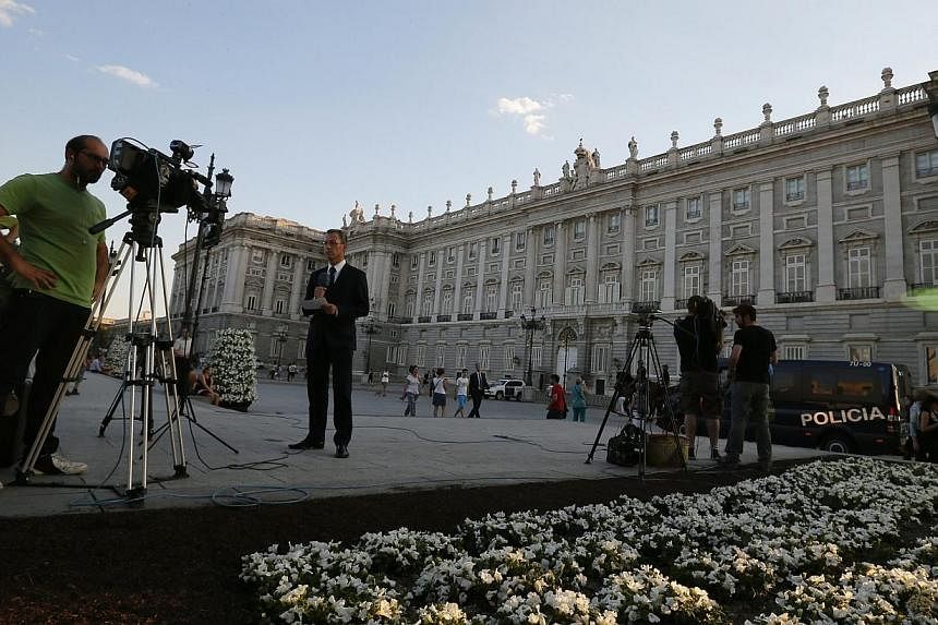 Journalists work as police officers patrol outside the Royal Palace in Madrid on June 17, 2014.&nbsp;Spain's King Juan Carlos signs an act of abdication on Wednesday, June 18, 2014, to end his 39-year reign, as a flag-festooned Madrid spruces up its 