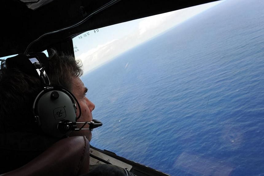 In this file photo taken on April 13, 2014 from a Royal New Zealand Airforce (RNZAF) P-3K2-Orion aircraft, co-pilot and Squadron Leader Brett McKenzie helps to look for objects during the search for missing Malaysia Airlines flight MH370, off Perth.&