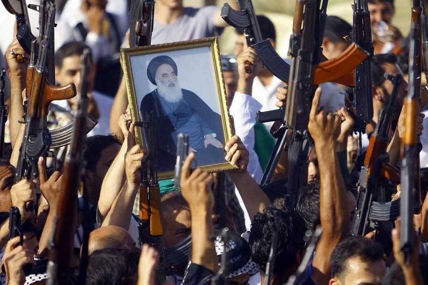 Iraqi Shiite tribesmen brandish their weapons and a poster of Shiite cleric Grand Ayatollah Ali al-Sistani as they gather to show their willingness to join Iraqi security forces in the fight against Jihadist militants who have taken over several nort