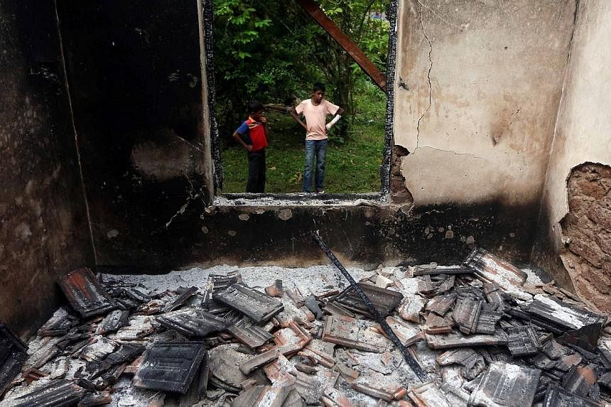 Muslim boys stand next to a burnt house after clashes between Buddhists and Muslims in Aluthgama on June 16, 2014. At least three Muslims were killed and 75 people seriously injured in violence between Buddhists and Muslims in southern Sri Lankan coa