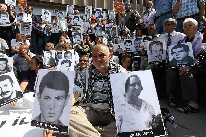 Turkish leftist demonstrators hold pictures of people who were executed or died in jail during the military rule that followed the 1980 coup in Turkey, in front of a courthouse in Ankara on June 18, 2014.&nbsp;A Turkish court on Wednesday handed life