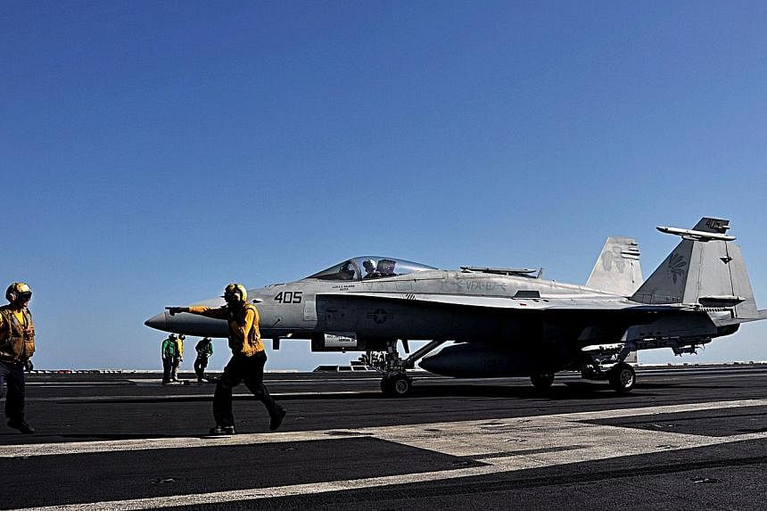 In this image released by the US Navy, sailors direct an F/A-18C Hornet on the flight deck of the aircraft carrier USS George H.W. Bush during flight operations in the Arabian Gulf on June 17, 2014. -- PHOTO: AFP