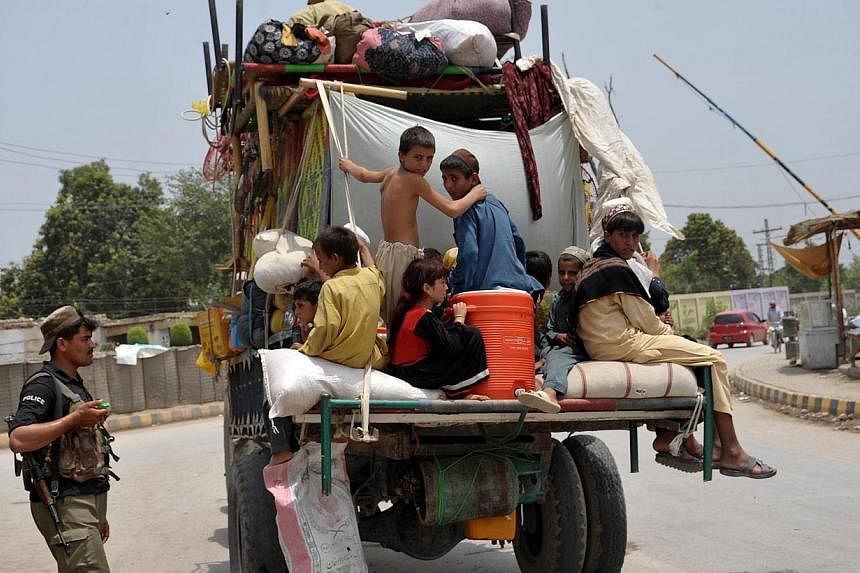 Pakistani civilians, fleeing from a military operation in North Waziristan tribal agency, cross a checkpoint as they arrive in Bannu district on June 19, 2014.&nbsp;Civilians are streaming out of a Pakistani tribal area in a two-pronged exodus ahead 