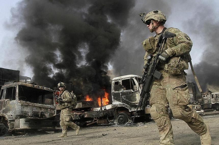 Nato troops walk near burning Nato supply trucks after, what police officials say, was an attack by militants in the Torkham area near the Pakistani-Afghan in Nangarhar Province on June 19, 2014.&nbsp;Four Taleban militants struck a Nato post in the 